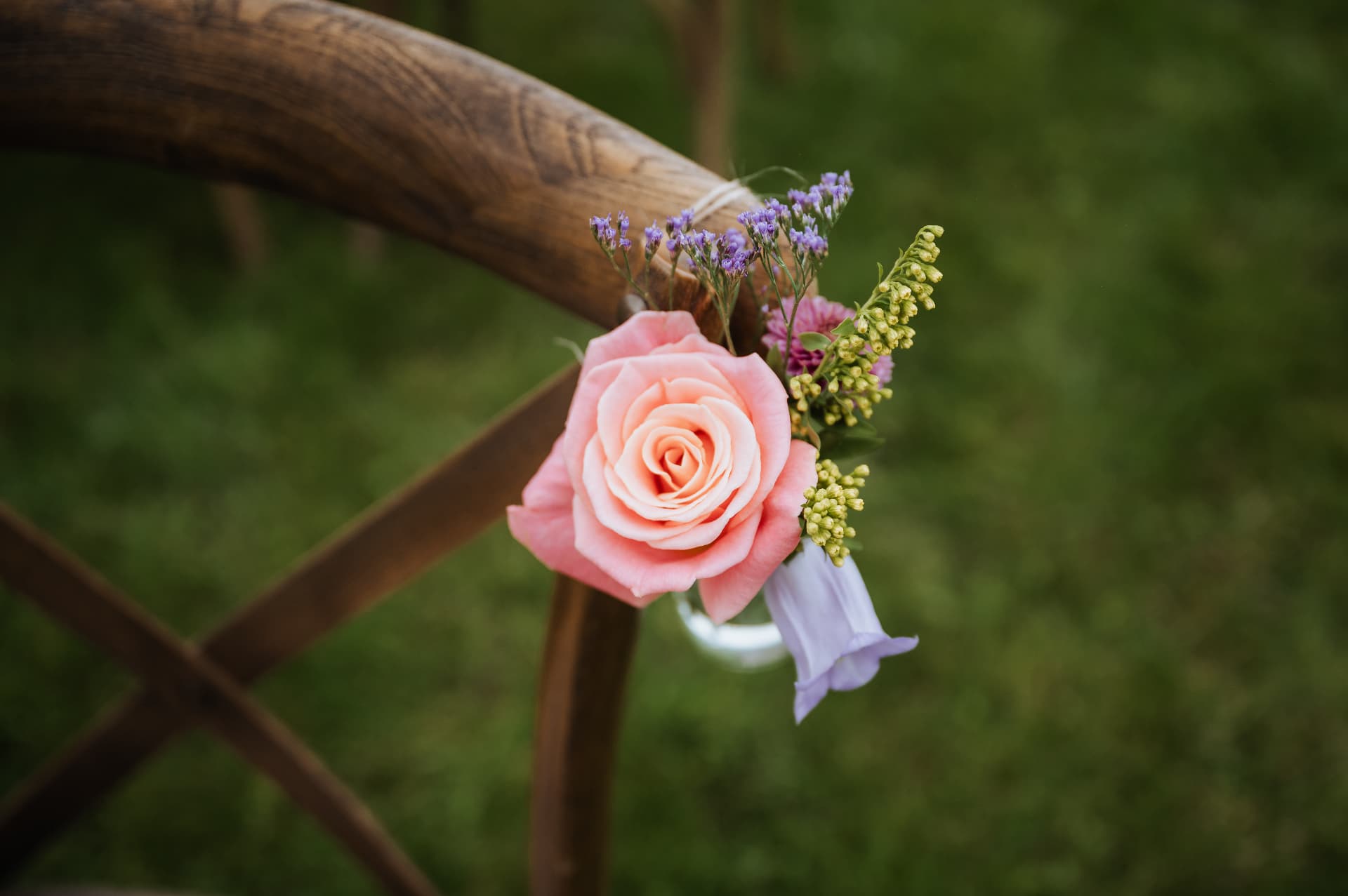 Stoeldecoratie met een roze roos en veldbloemen