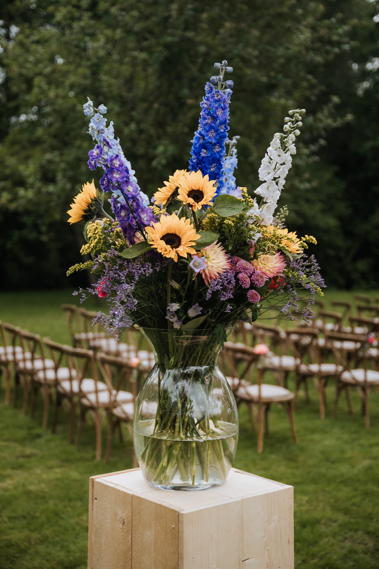 Grote vaas met zonnebloemen en ridderspoor bij een ceremonie