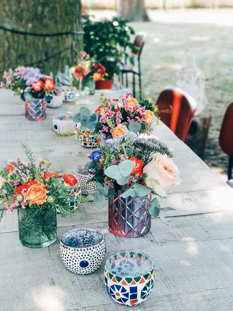 Kleurrijke tafeldecoratie met bloemen in glazen potjes