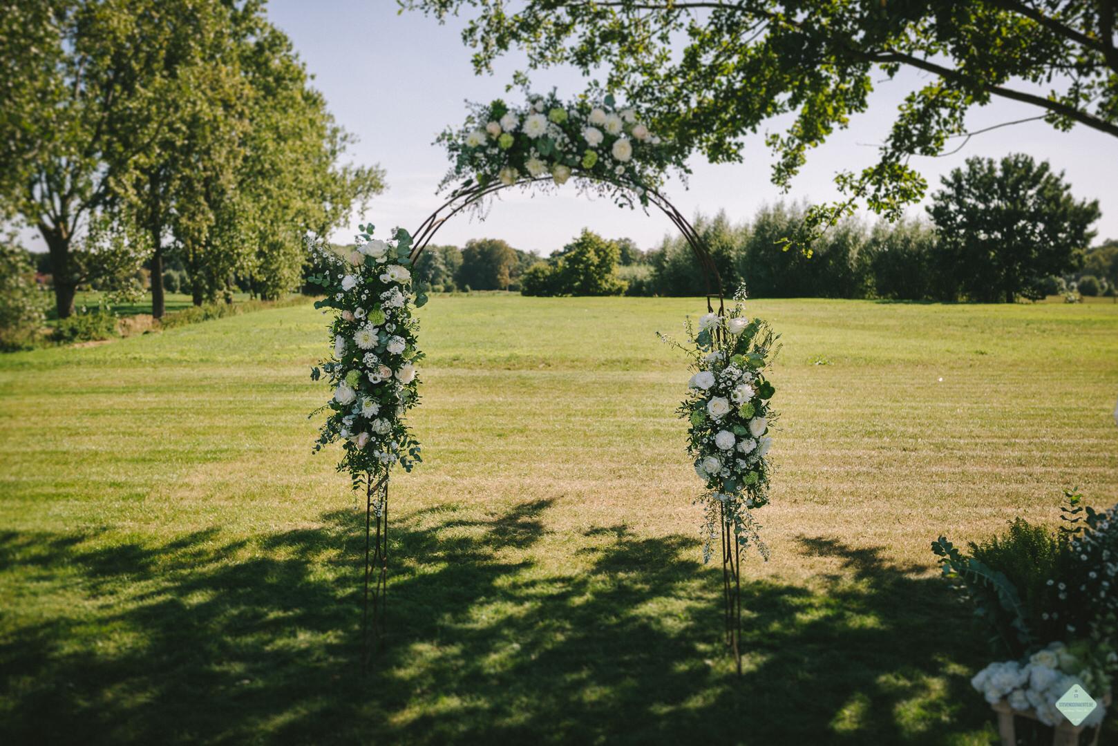 Bloemenboog met witte en groene bloemen in een weide